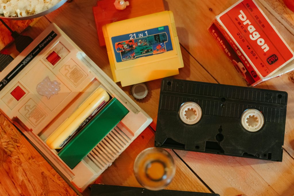 Vintage gaming console with cartridges and VHS tape on wooden surface, nostalgic theme.